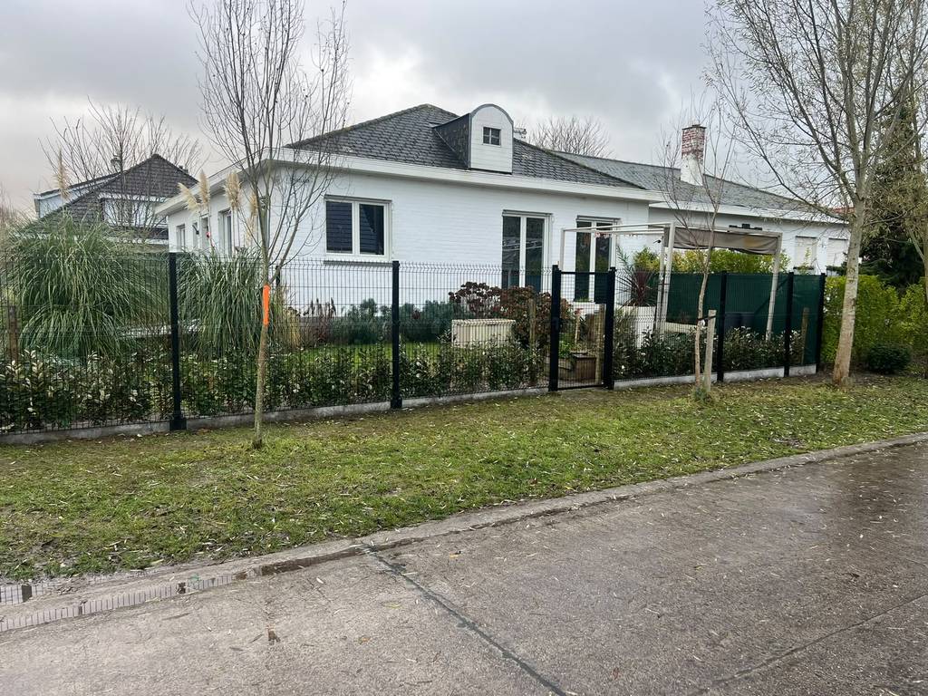 Zwarte omheining met draadpanelen en een tuinpoort rond een voortuin